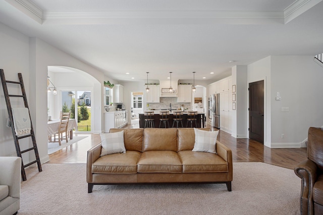 12816 Cedar Ridge Ln, Champlin, MN 55316 - carpeted living room featuring arched walkways, a raised ceiling, crown molding, recessed lighting, and wood finished floors