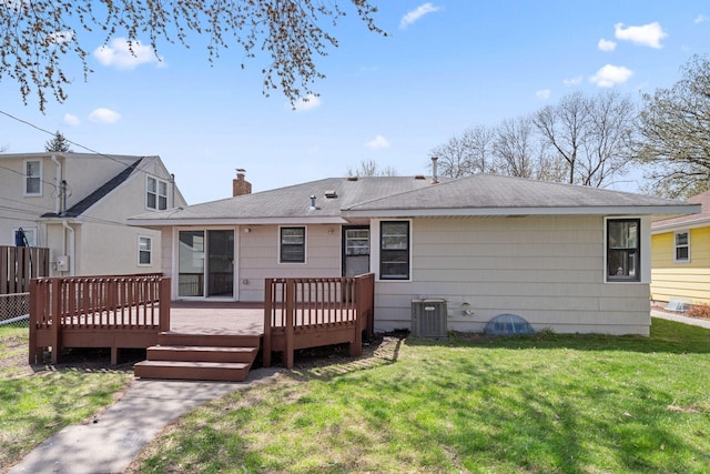 rear view of property featuring roof with shingles, a wooden deck, a chimney, and a yard