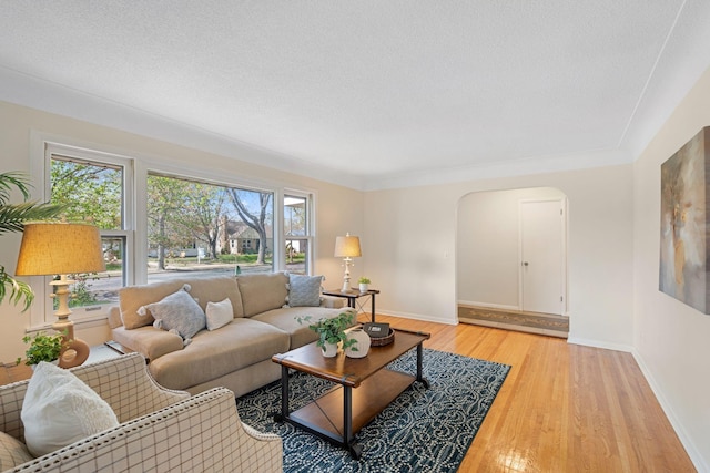 living area featuring arched walkways, baseboards, and light wood-style flooring