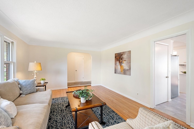living room featuring light wood-style floors, arched walkways, and baseboards