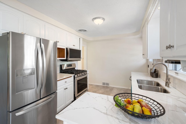 kitchen featuring a sink, appliances with stainless steel finishes, decorative backsplash, and visible vents