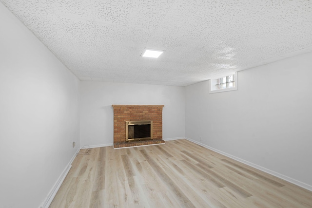 unfurnished living room with baseboards, a textured ceiling, light wood-style flooring, and a fireplace