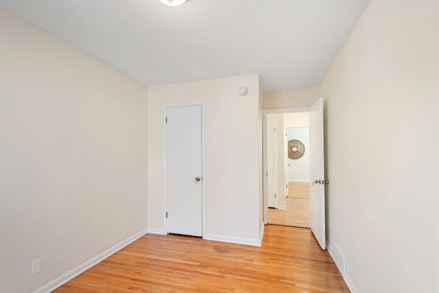 unfurnished bedroom with baseboards, light wood-style flooring, and visible vents