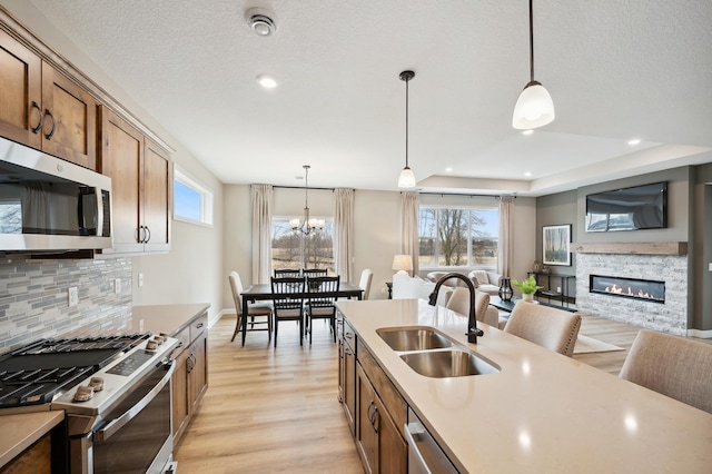 19999 Hunters Rdg, Corcoran, MN 55374 - kitchen featuring stainless steel appliances, a sink, open floor plan, tasteful backsplash, and decorative light fixtures