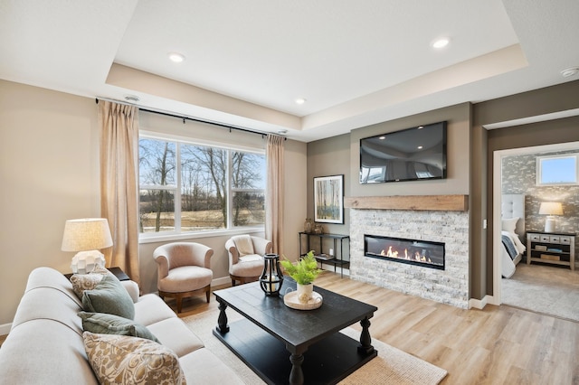 19999 Hunters Rdg, Corcoran, MN 55374 - living room featuring light wood-type flooring, a fireplace, recessed lighting, a tray ceiling, and baseboards