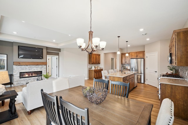 19999 Hunters Rdg, Corcoran, MN 55374 - dining area featuring light wood-style flooring, a stone fireplace, recessed lighting, and a chandelier