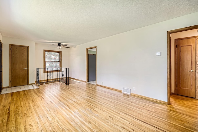 11352 Olive St NW, Coon Rapids, MN 55448 - unfurnished room with light wood-style flooring, a textured ceiling, ceiling fan, and baseboards
