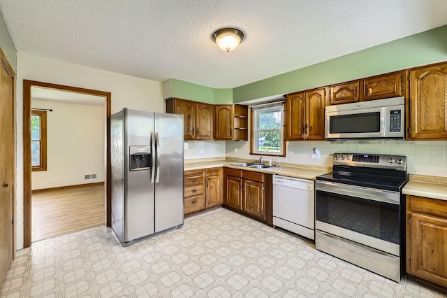 11352 Olive St NW, Coon Rapids, MN 55448 - kitchen featuring stainless steel appliances, a sink, open shelves, light countertops, and a textured ceiling