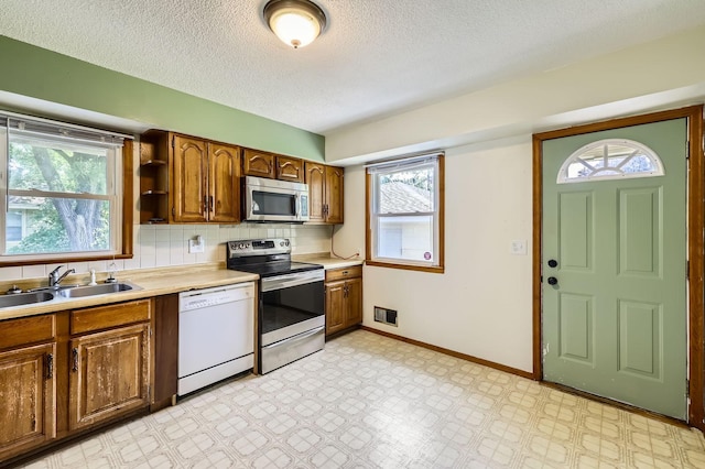 11352 Olive St NW, Coon Rapids, MN 55448 - kitchen with appliances with stainless steel finishes, a sink, light countertops, a textured ceiling, and decorative backsplash