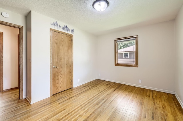11352 Olive St NW, Coon Rapids, MN 55448 - unfurnished bedroom with light wood-type flooring, baseboards, a textured ceiling, and a closet