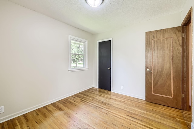 11352 Olive St NW, Coon Rapids, MN 55448 - unfurnished bedroom featuring baseboards, light wood-type flooring, and a textured ceiling