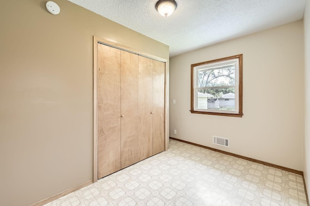 11352 Olive St NW, Coon Rapids, MN 55448 - unfurnished bedroom featuring a closet, a textured ceiling, light floors, and baseboards
