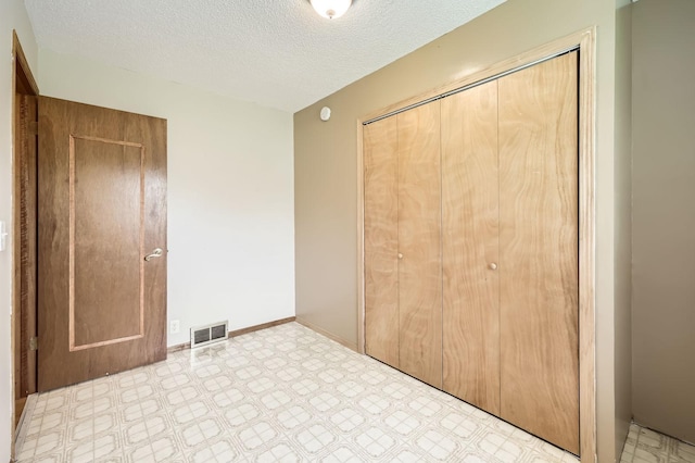 11352 Olive St NW, Coon Rapids, MN 55448 - unfurnished bedroom featuring a closet, a textured ceiling, tile patterned floors, and baseboards