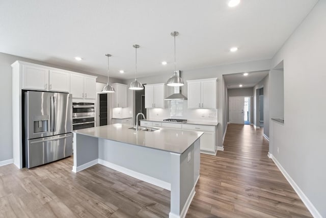 kitchen with stainless steel appliances, a sink, recessed lighting, light wood-type flooring, and a kitchen island with sink