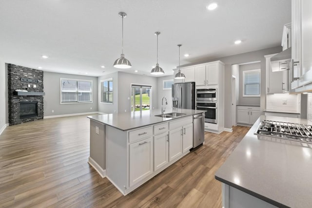 kitchen featuring stainless steel appliances, a sink, recessed lighting, white cabinets, and light wood-style floors