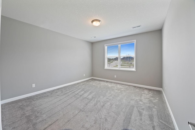 spare room featuring carpet, a textured ceiling, and baseboards