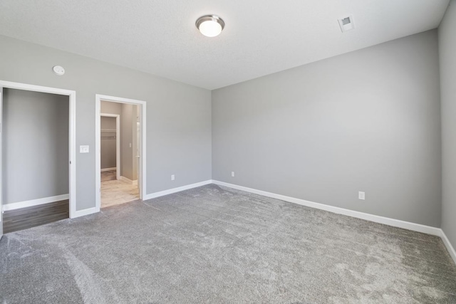 unfurnished bedroom featuring carpet floors, baseboards, and a walk in closet