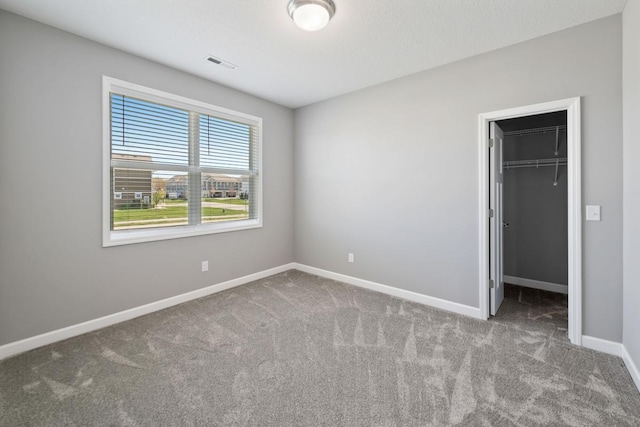 unfurnished bedroom with carpet, baseboards, a walk in closet, and a closet