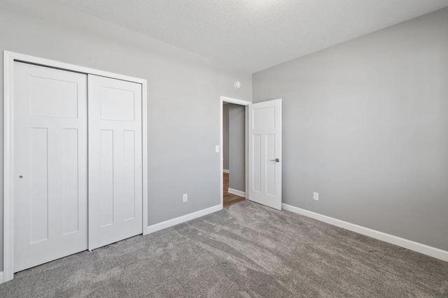 unfurnished bedroom featuring carpet, baseboards, a closet, and a textured ceiling