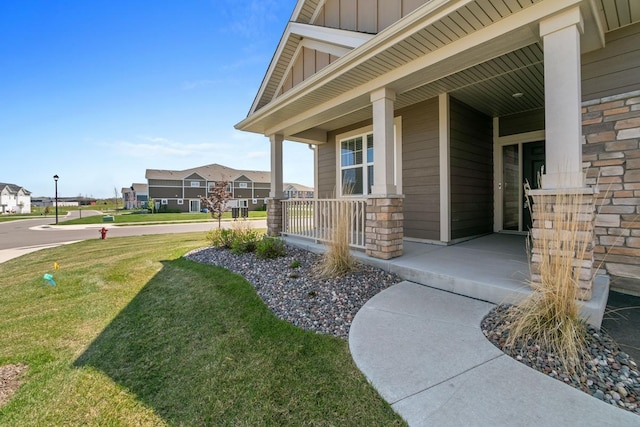 entrance to property with a porch, a residential view, board and batten siding, and a lawn