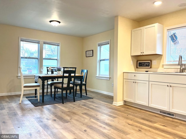 dining room with plenty of natural light, light wood-style flooring, and baseboards