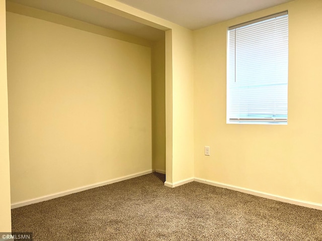 empty room with baseboards and dark carpet