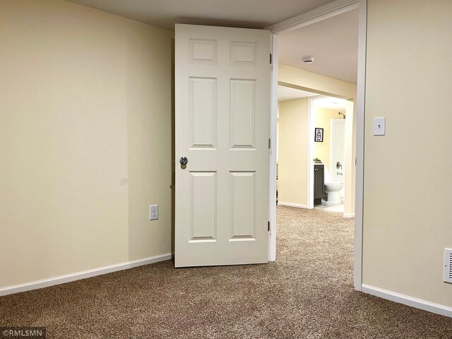 unfurnished room with dark colored carpet and baseboards