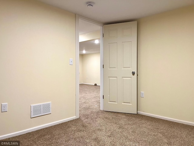 carpeted empty room featuring baseboards and visible vents