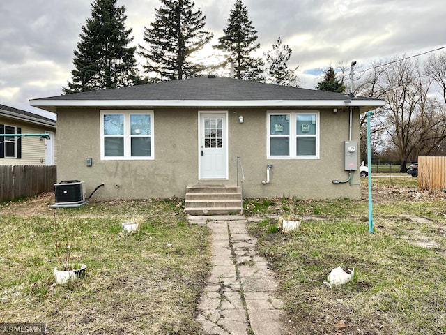 bungalow-style house with stucco siding, central AC unit, fence, and entry steps