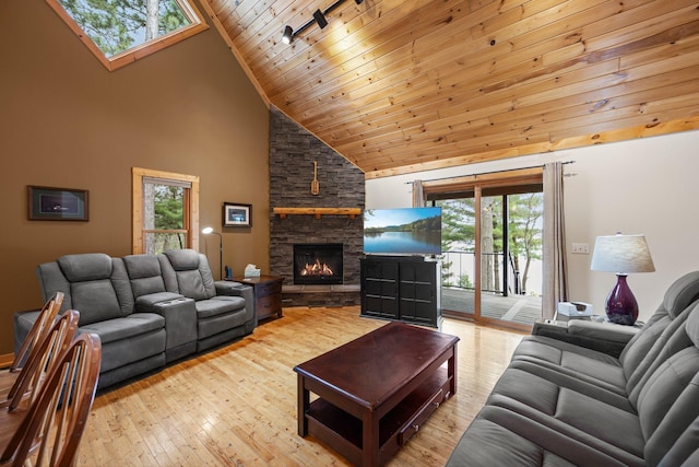living area featuring high vaulted ceiling, track lighting, wooden ceiling, wood-type flooring, and a stone fireplace