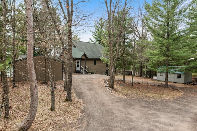 view of front of home with roof with shingles, a storage shed, an outbuilding, and driveway
