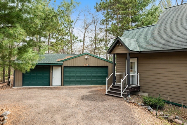 view of front of property with a shingled roof, an outbuilding, and a detached garage
