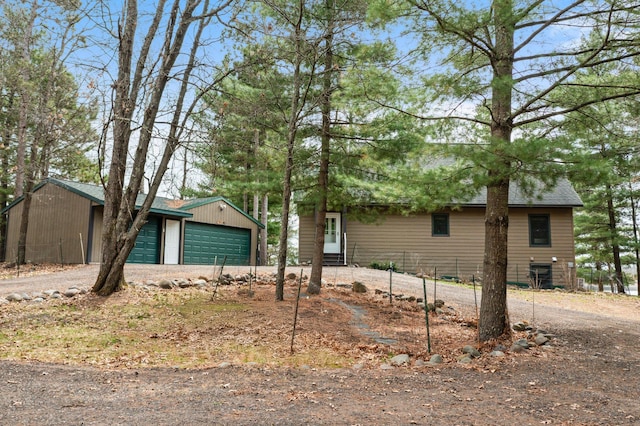 view of front of house featuring a garage, an outdoor structure, dirt driveway, and entry steps