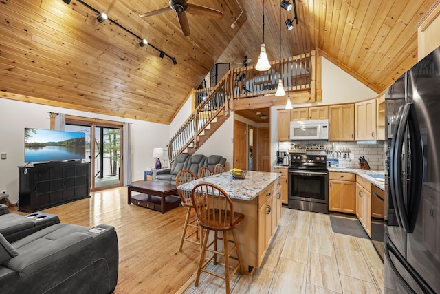 kitchen featuring freestanding refrigerator, stainless steel range with electric stovetop, open floor plan, and white microwave