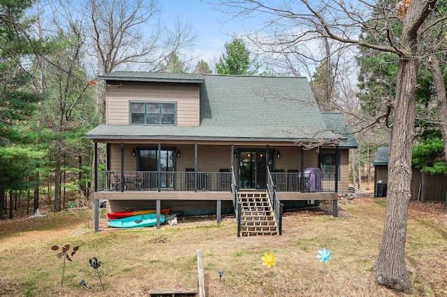 rustic home featuring covered porch, roof with shingles, a front yard, and stairs