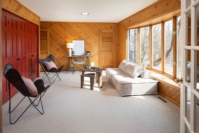 interior space with visible vents, carpet flooring, and wooden walls