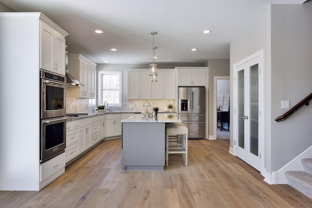 3542 Leroy St, Deephaven, MN 55391 - kitchen featuring appliances with stainless steel finishes, decorative backsplash, a center island, a breakfast bar area, and light wood-style flooring