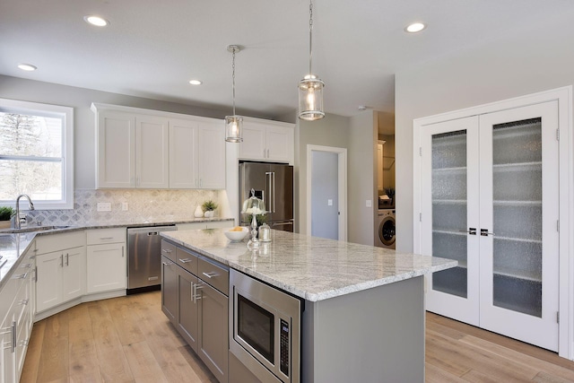 3542 Leroy St, Deephaven, MN 55391 - kitchen with appliances with stainless steel finishes, a sink, washer / clothes dryer, backsplash, and light wood finished floors