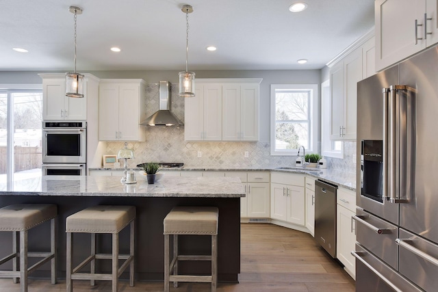 3542 Leroy St, Deephaven, MN 55391 - kitchen with stainless steel appliances, wall chimney range hood, a sink, a breakfast bar area, and recessed lighting