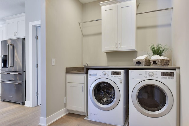 3542 Leroy St, Deephaven, MN 55391 - laundry area featuring separate washer and dryer, light wood-style flooring, cabinet space, and baseboards