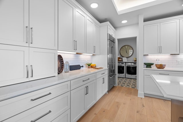 kitchen with decorative backsplash, high end fridge, wall oven, recessed lighting, and white cabinetry