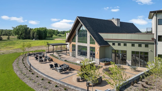 back of property with roof with shingles, stone siding, a patio area, a standing seam roof, and metal roof