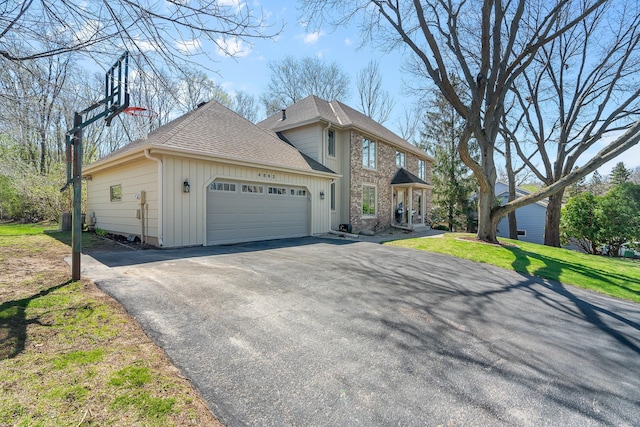 colonial-style house with aphalt driveway, central AC, a front yard, roof with shingles, and an attached garage