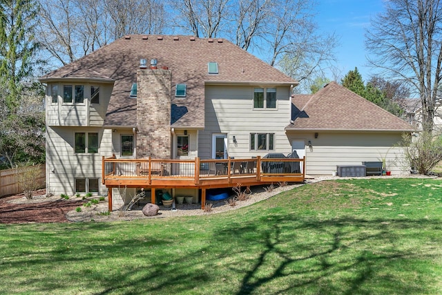 back of property featuring a lawn, a chimney, a shingled roof, and a deck