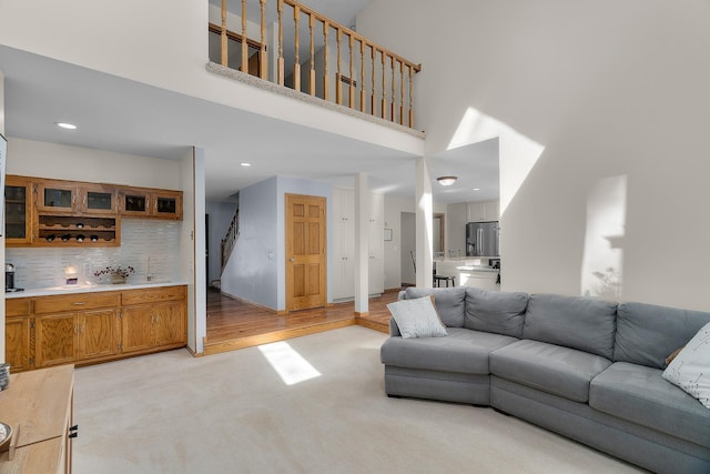 living room with stairs, recessed lighting, a high ceiling, and light wood-type flooring