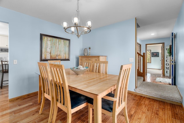 dining space with baseboards, a chandelier, and light wood-type flooring
