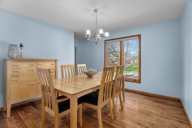 dining room featuring baseboards, light wood finished floors, and a notable chandelier