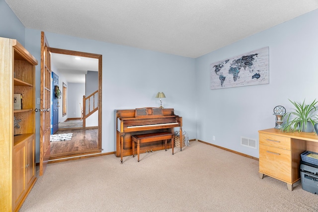 living area with visible vents, a textured ceiling, carpet, and baseboards