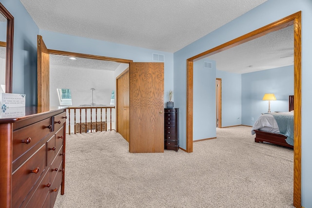 hall featuring carpet floors, a textured ceiling, and visible vents