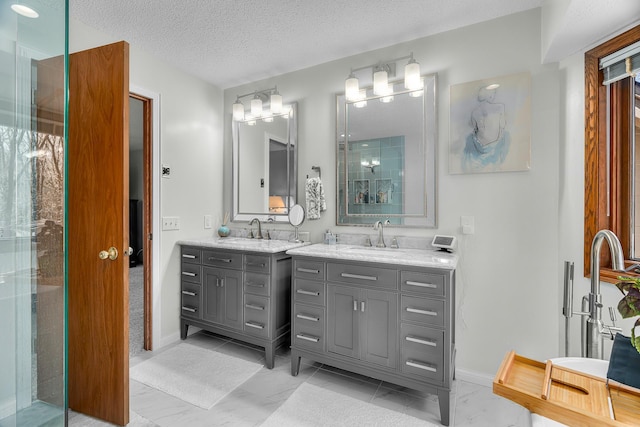 bathroom featuring a sink, baseboards, a shower with door, and two vanities